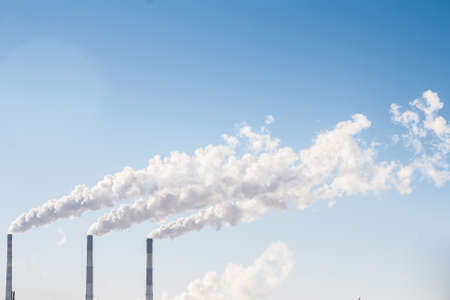 industrial smoke comes out of a chimney  against  the  blue skyの写真素材