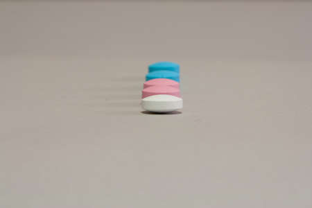 Colored pills in a row on gray paperの写真素材