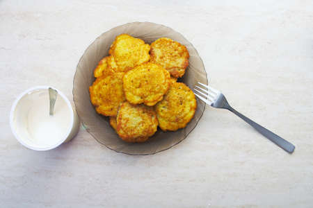 A plate of potato pancakes and sour cream on the table next toの写真素材