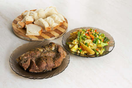 Two plates with baked meat and assorted fruits and homemade breadの写真素材