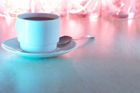 Coffee cup in multicolored light on tableの写真素材