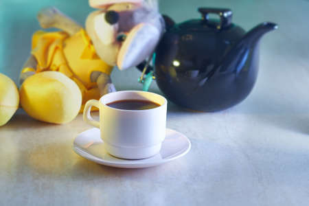 Coffee cup and kettle with toy on tableの写真素材