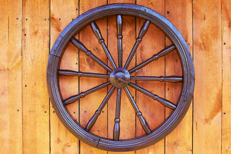 Hand spinning wheel on the wall of the old log house in the village.の写真素材