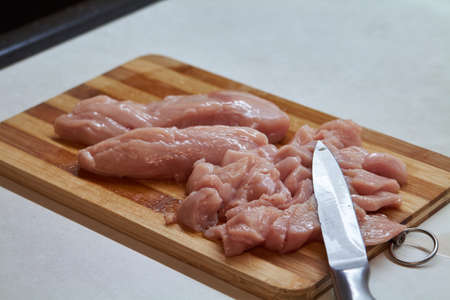 Slicing chicken breast on chopping broad into stripsの写真素材