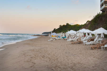 Empty beach on the seaside at the end of resort season with many empty sun loungers and umbrellas in the eveningの写真素材
