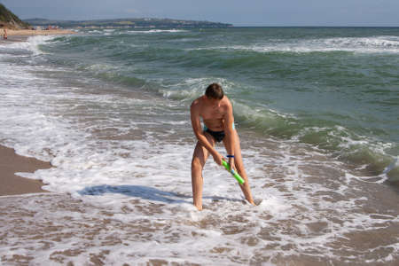 Teen with a water gun at seaの写真素材