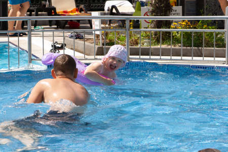 A girl with an inflatable circle and a boy play in the pool.の写真素材