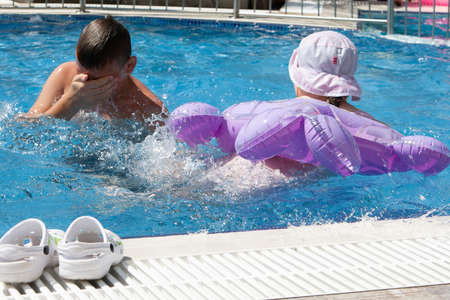 A girl with an inflatable circle and a boy play in the pool.の写真素材