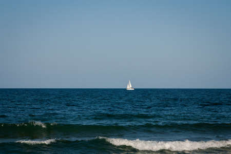 Beautiful seascape, dark blue sea on high mountains background, luxury yacht floating in the distance, summer vacation conceptの写真素材