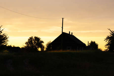 Silhouettes of trees and houses against the backdrop of the setting sun.の写真素材