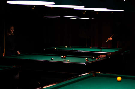 Billiard room with tables and players around them