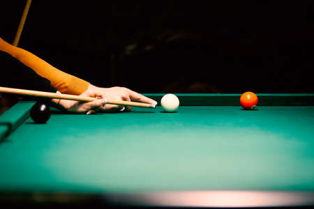 billiard green table in hall with white balls with men handの写真素材
