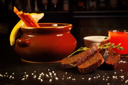 Restaurant serving of a dish - a pot of hodgepodge and black bread with a glass of alcoholの写真素材