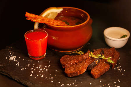 Restaurant serving of a dish - a pot of hodgepodge and black bread with a glass of alcoholの写真素材