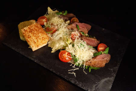 Restaurant serving snacks on the board - fried bread, meat, finely chopped cheese, tomatoes and greens.の写真素材
