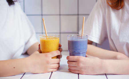 Hands of two girls are sitting in a cafe with smoothies on tables in a cafe.の写真素材