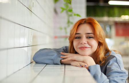 A young charming red-haired girl in a cafe with a beautiful look is sitting