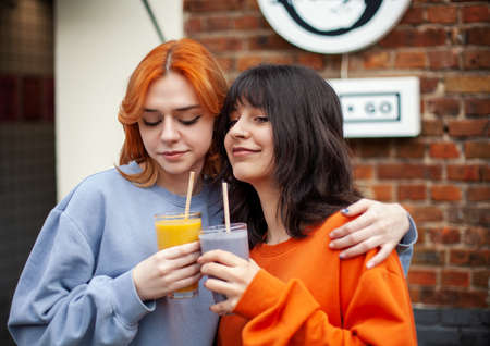 Portrait of two young friends having fresh juice and talking.の写真素材