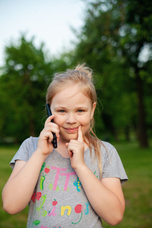 A young girl smiles with her phone in a park in natureの写真素材