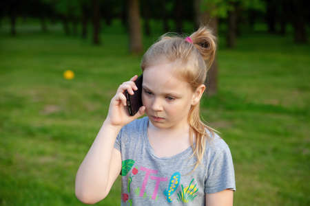 A young girl smiles with her phone in a park in nature