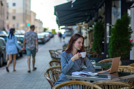 Beautiful professional ht manager woman in a fashion business suit working on a laptop and drinking coffeeの写真素材