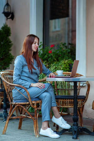 Beautiful confident woman. Woman on the street at the table . Business consultant, to note down, to make notes. Business meeting. Woman with notebook. Business look.の写真素材