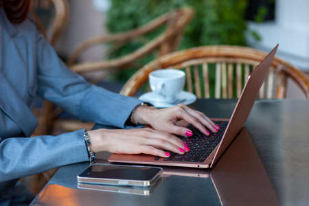 Close up cropped photo of business woman sitting with laptop and cup of coffee