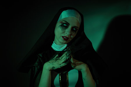 Halloween. Portrait of a scary devilish nun eyes looking at camera on a black and green background.の写真素材