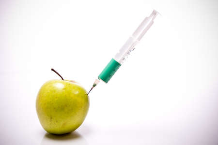 a green apple and syringe with coloured liquidの写真素材