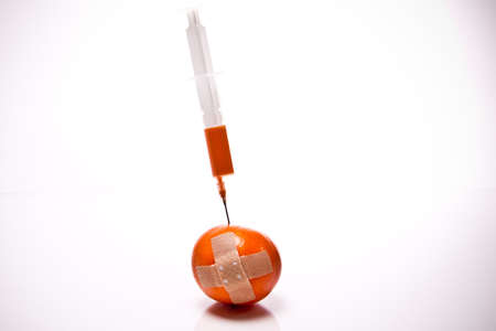 a orange with Plaster and syringe in front of white backgroundの写真素材