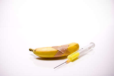 a banana with Plaster and syringe in front of white backgroundの写真素材