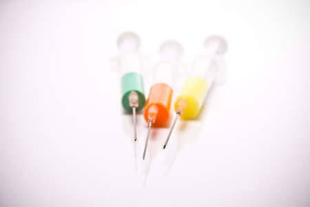 syringe with coloured liquid in front of white backgroundの写真素材