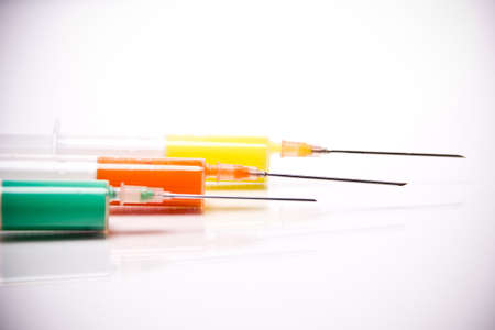 syringe with coloured liquid in front of white backgroundの写真素材