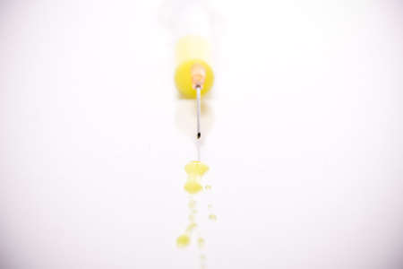 syringe with coloured liquid in front of white backgroundの写真素材