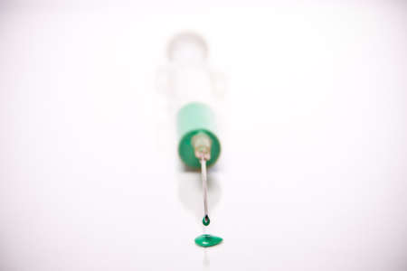 syringe with coloured liquid in front of white backgroundの写真素材