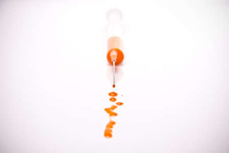 syringe with coloured liquid in front of white backgroundの写真素材
