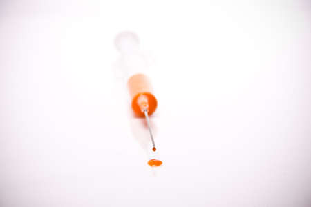 syringe with coloured liquid in front of white backgroundの写真素材