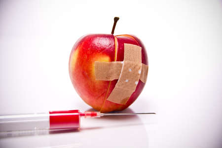 a sliced apple with a plaster in front of white backgroundの写真素材