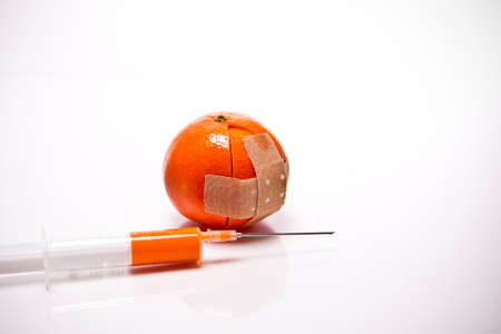 a sliced orange with a plaster in front of white backgroundの写真素材