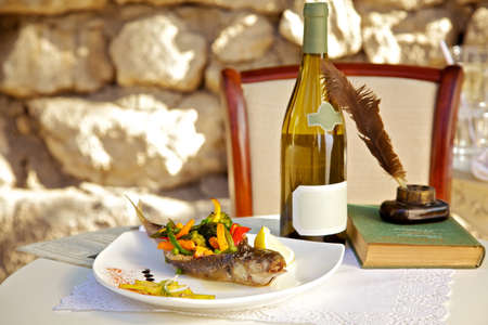 On the table stuffed fish with vegetables and a bottle of white wine