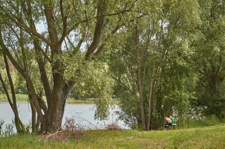 Two girls are sitting on a bench on the shore of the bayの写真素材