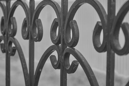 The fence is made of black wrought iron with a horseshoe patternの写真素材
