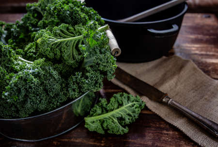 Green kale in basket and knife on wooden backgroundの写真素材