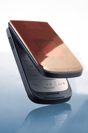 Opened vertical phone on cyan/white background with reflexの写真素材