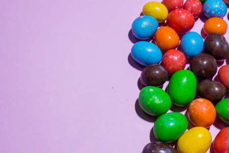 Close up of colorful green blue orange red chocolate round candy on pink backgroundの写真素材