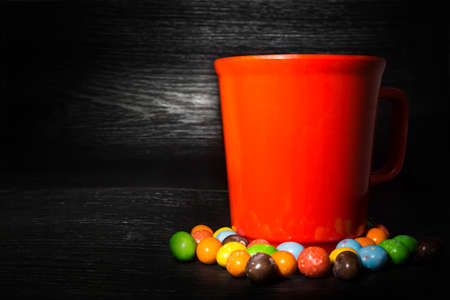 Colorful candy surround of red cup on black wooden texture backgroundの写真素材