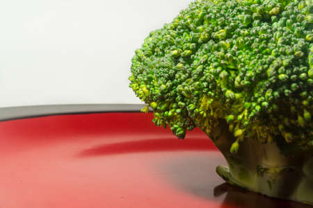 Green Brocolli on Red and Black Plate on White Backgroundの写真素材
