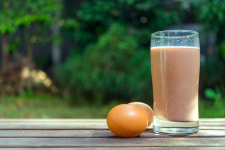 Chocolate Milk and Two Eggs on Wooden Ground on Green Backgroundの写真素材