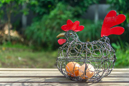 Two Eggs in Chicken Place Decoration on Wooden Ground on Green Background Taken From Front Angleの写真素材
