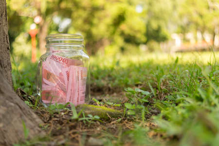 Hundred Thousand Rupiah Paper Money in jar on Green Nature Backgroundの写真素材
